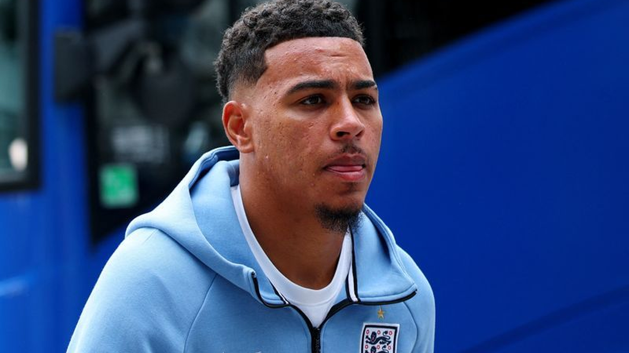 Morgan Rogers anländer med Englands trupp iklädd ett blått träningsoverallsklädsel